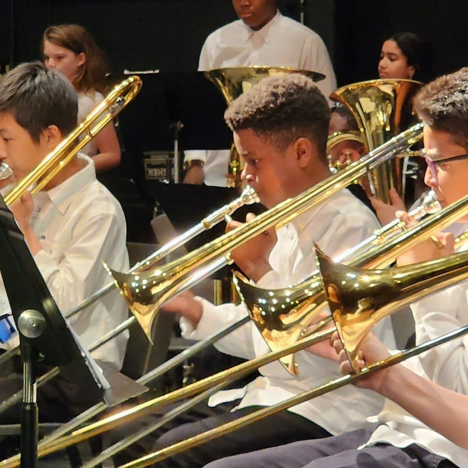 Students playing sitting down with a tuba and trombone