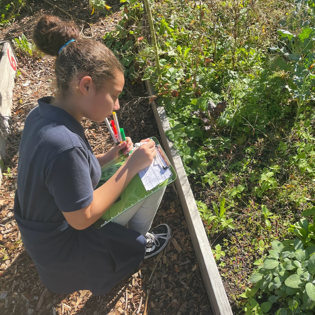 student gardening and taking notes