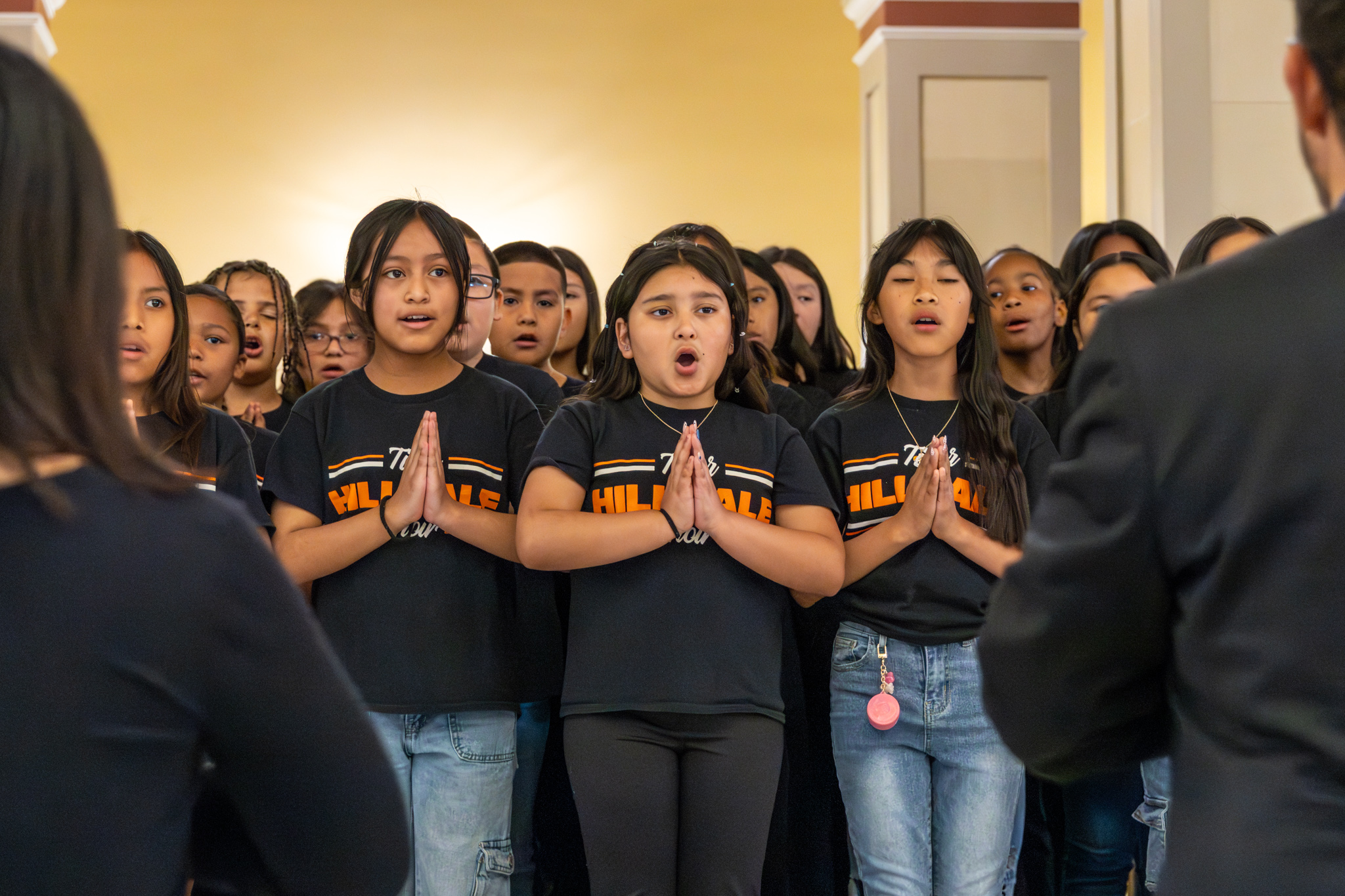 Choir students singing and moving their hands in choreographed motion