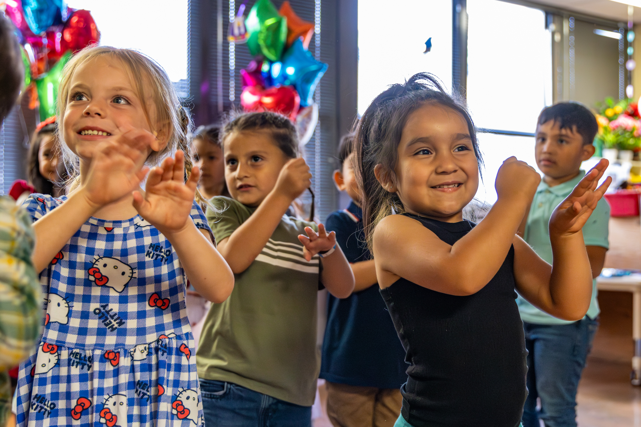 Children smile and perform hand motions while singing