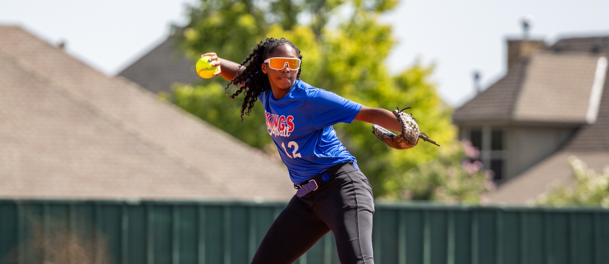 A student winds up to throw a softball across the infield.