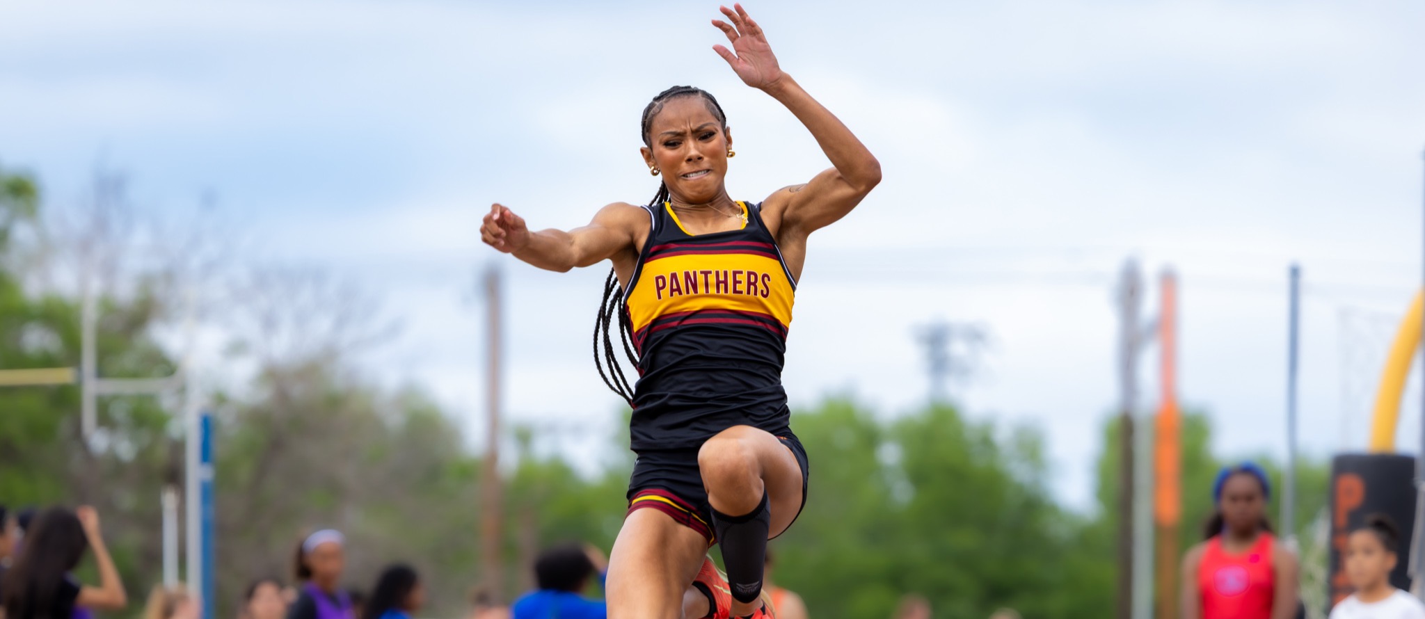 Female athlete jumps and holds her arms up for balance during a long jump