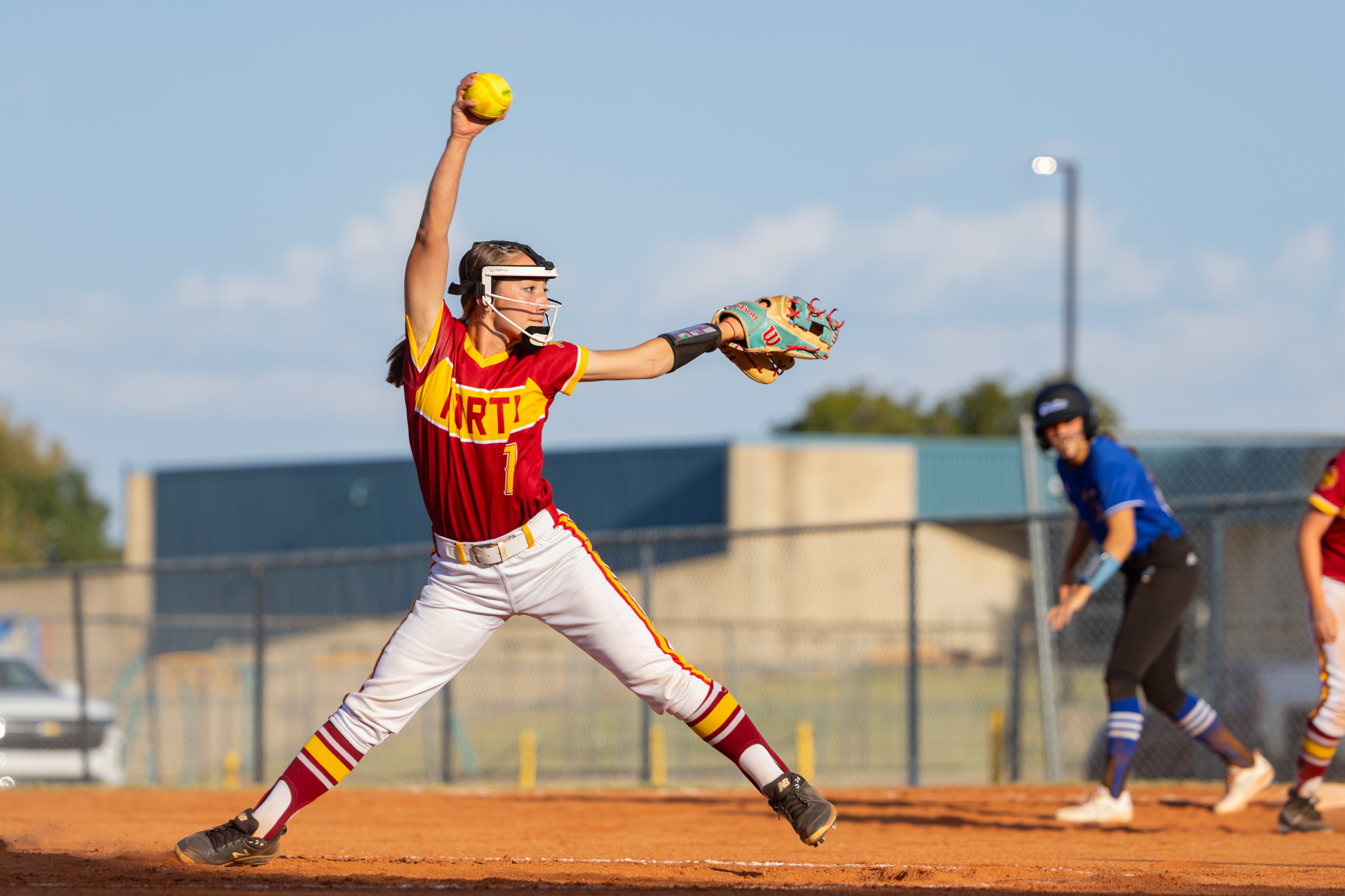 PCN softball player halfway through sending a pitch over home plate