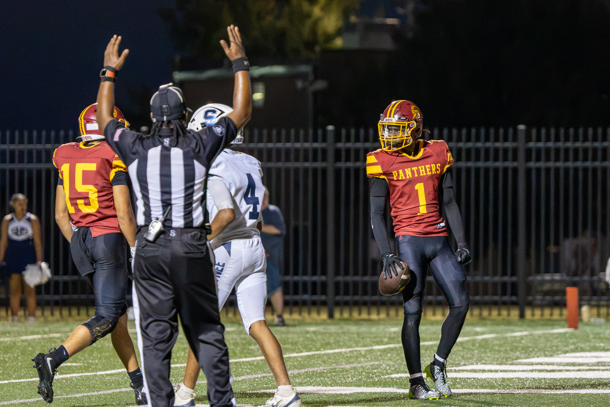 PCN football player holds the ball and looks to his teammates as the referee signals a touchdown