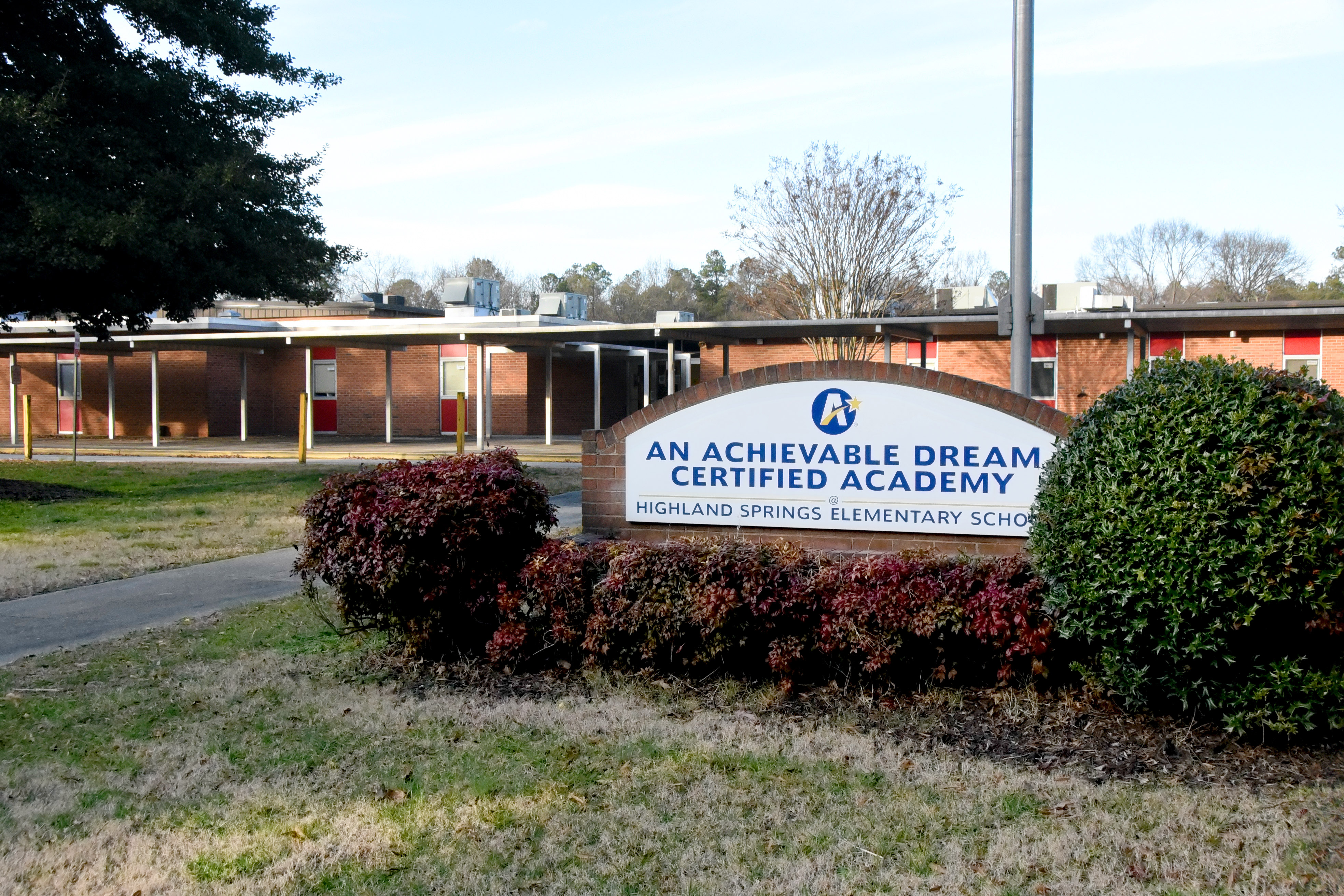 front sign reading: an achievable dream certified academy at highland springs elementary school surrounded by bushes