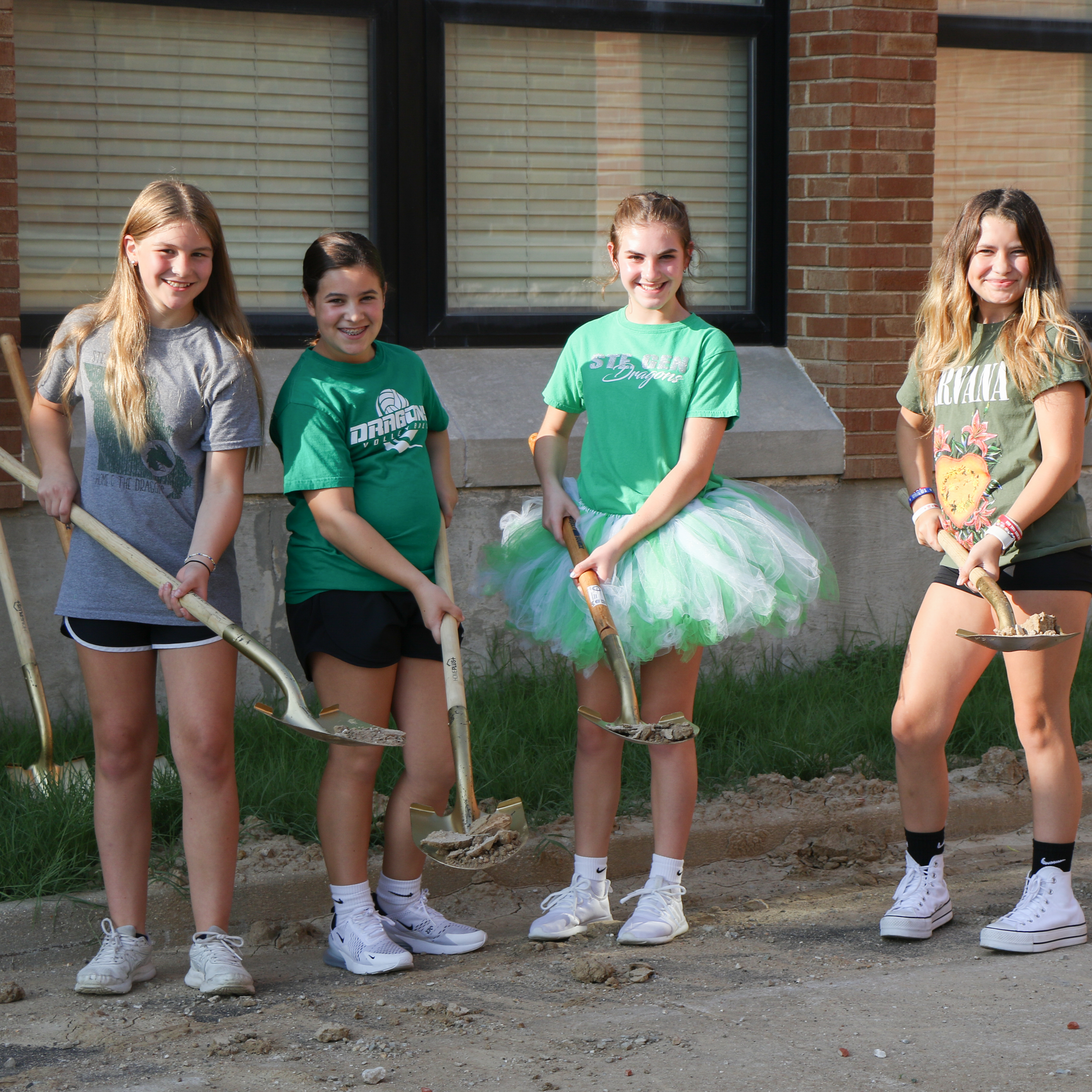 Four students hold shovels at the groundbreaking.