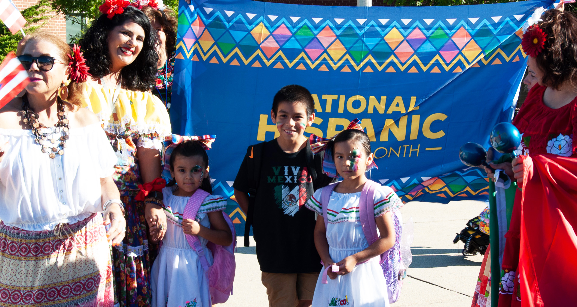 Hispanic Heritage month flag with teachers and students dressed in their nationalities attire.