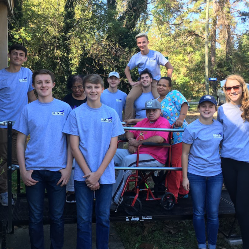 Students posing with a person using a wheelchair ramp