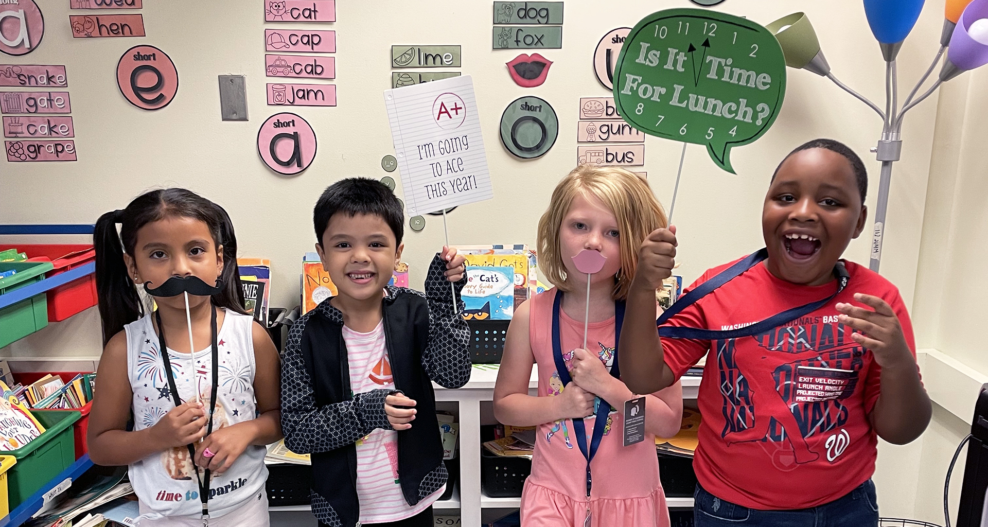 Four students pose with photo booth props for a fun picture