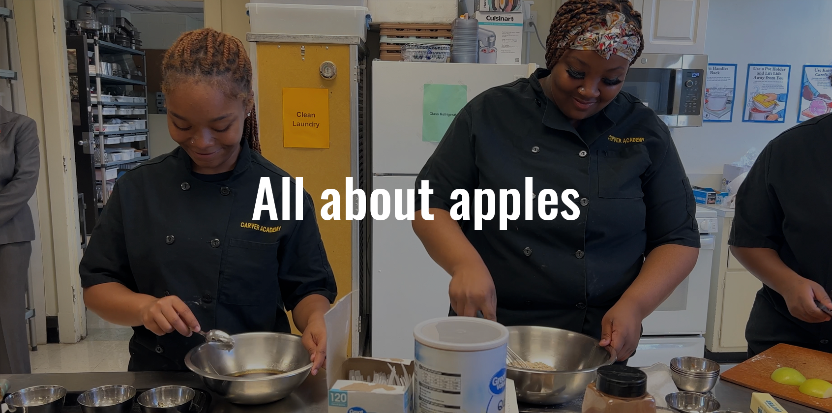 Two student cutting apples in class with text on the image that says "all about apples"