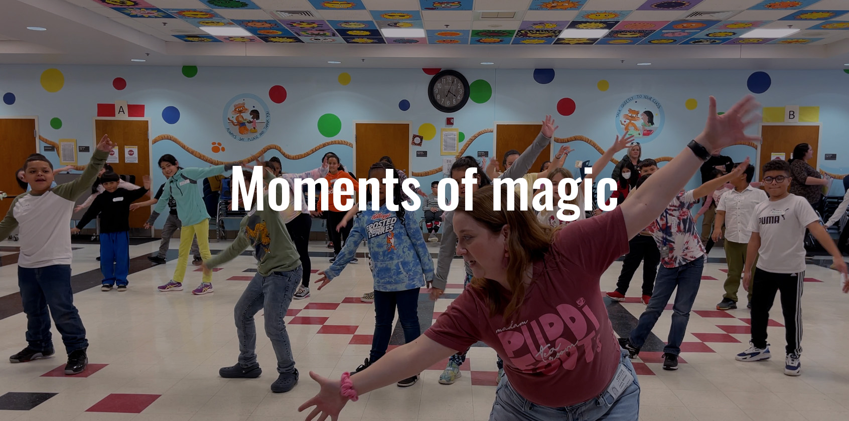 A volunteer guiding a group of students to learn a dance for a musical