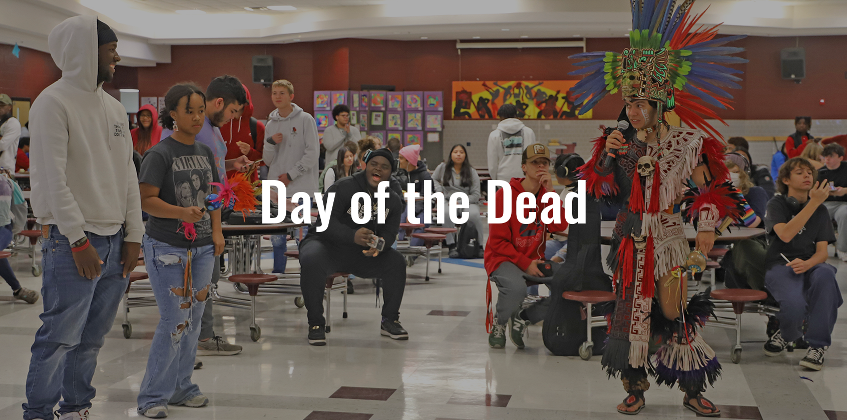 An Aztec dancer getting ready to teach high school students a dance, text on image says "Day of the Dead"
