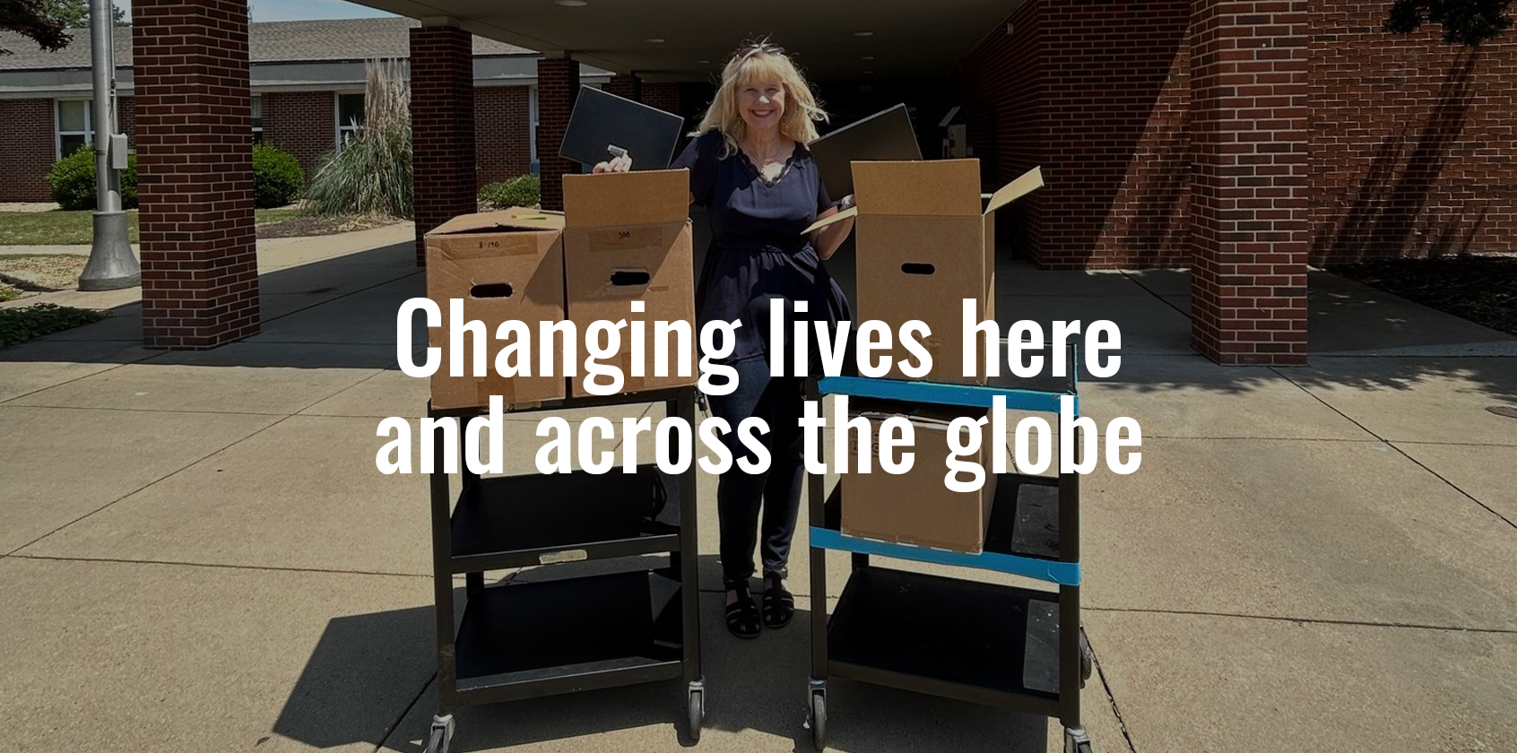 A teacher in front of two carts stacked with boxes