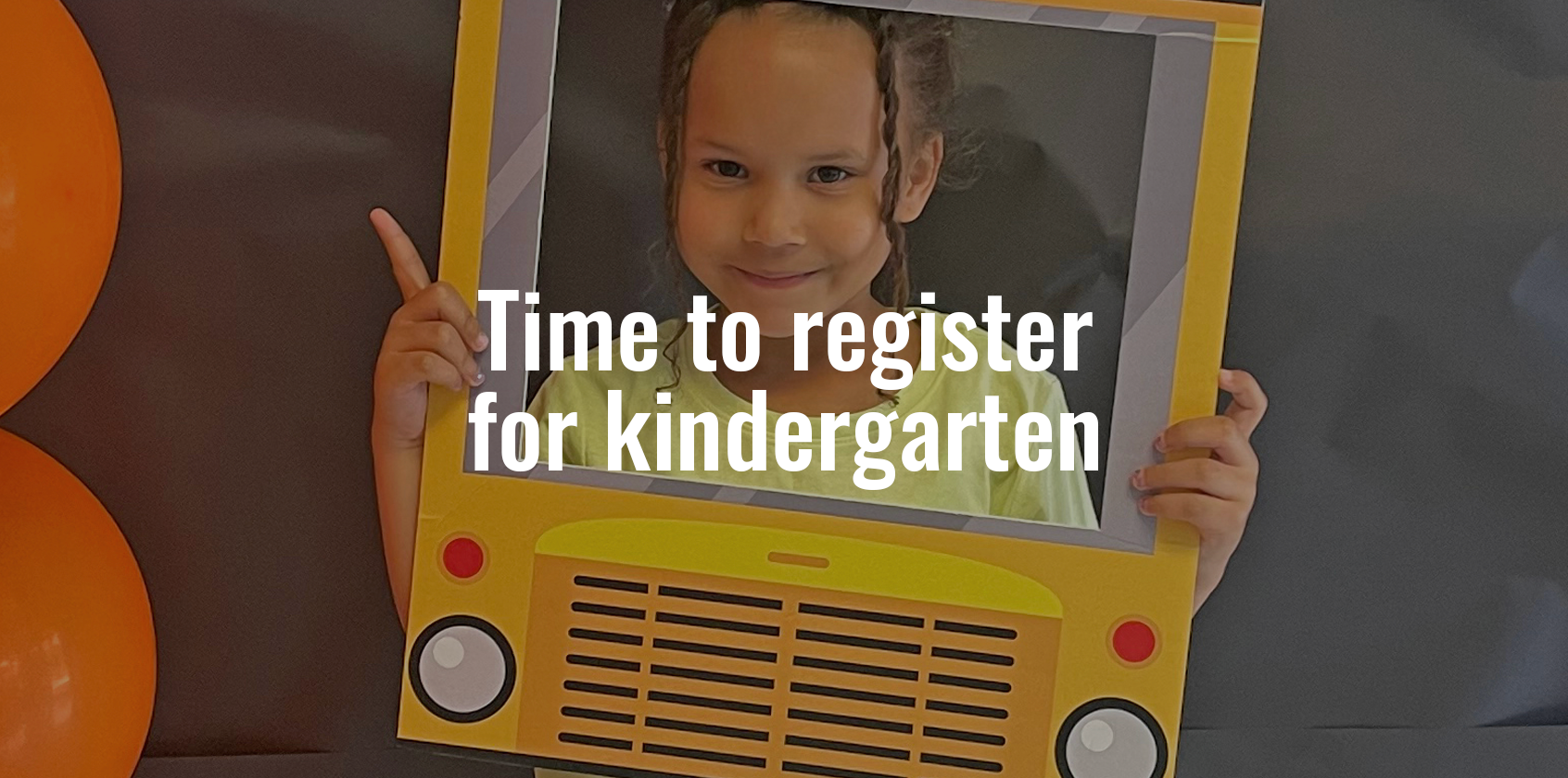 A student smiling while holding a cutout of the front of a school bus