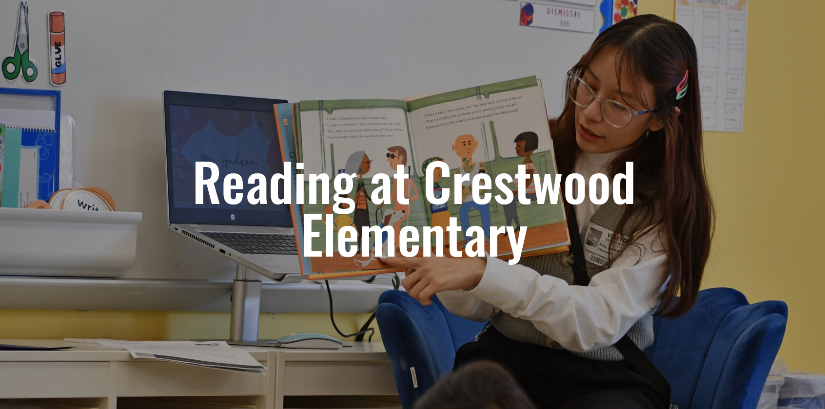 Teacher holding up a book and reading to the students.