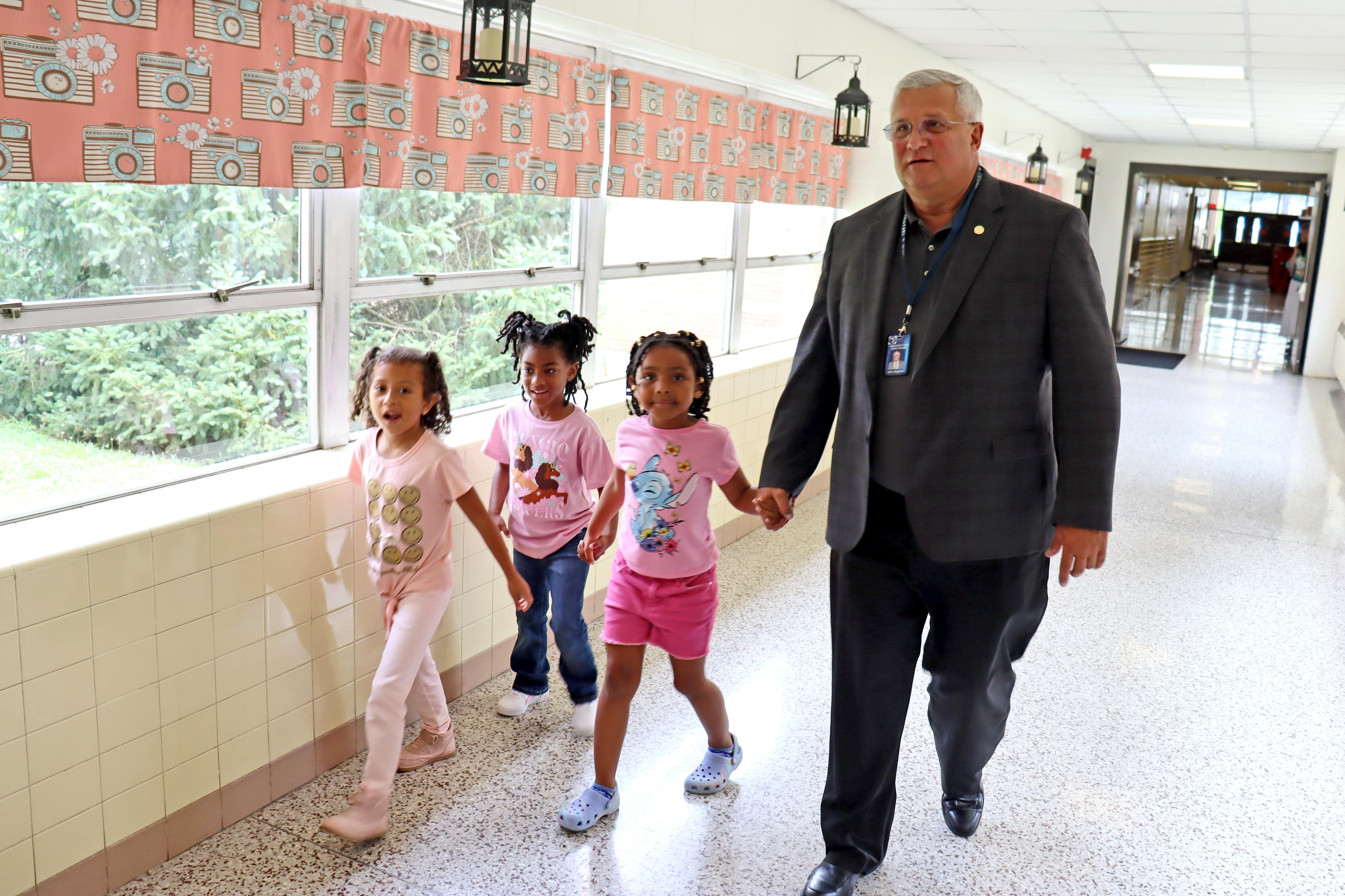 Superintendent walking with three students down the school hallway