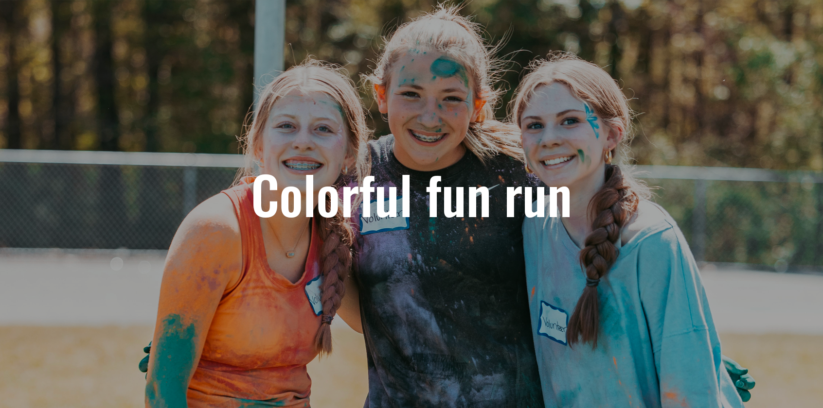 Three girls hugging each other during a colorful fun run with text that says "Colorful fun run"