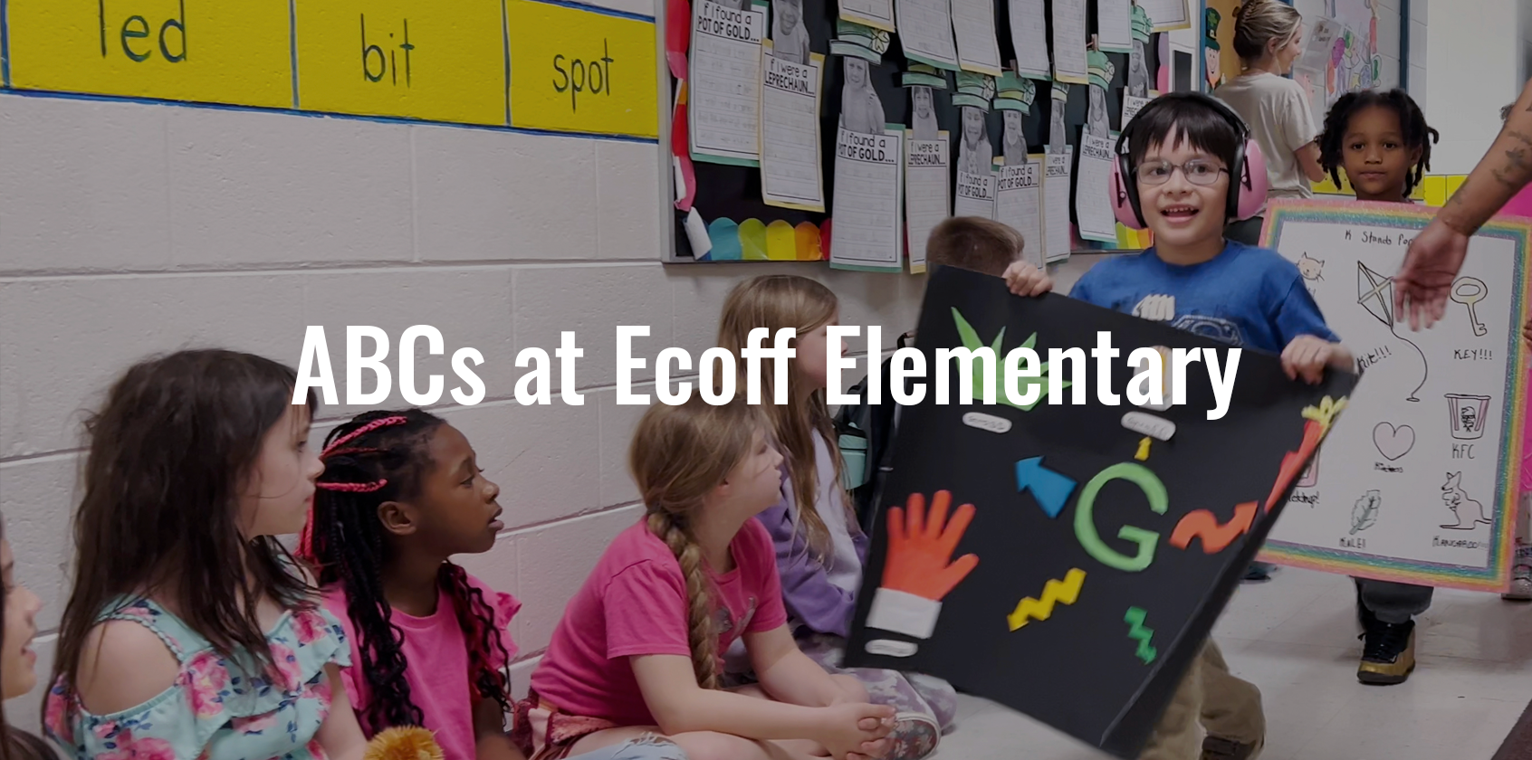 Students holding posters while walking down the hallway with text that says "ABCs at Ecoff Elementary"
