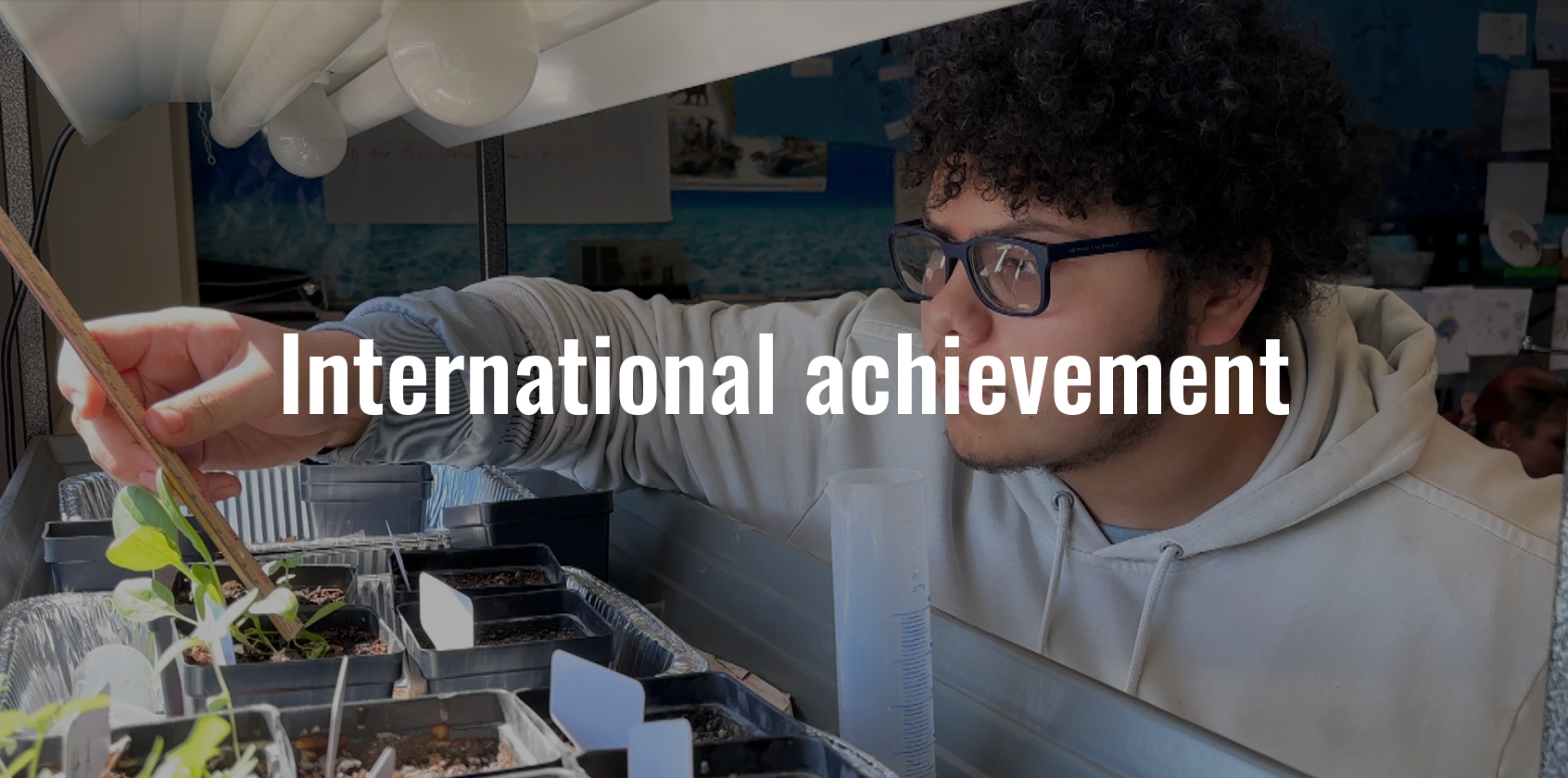 A student measuring a plant and text that says "International achievement"