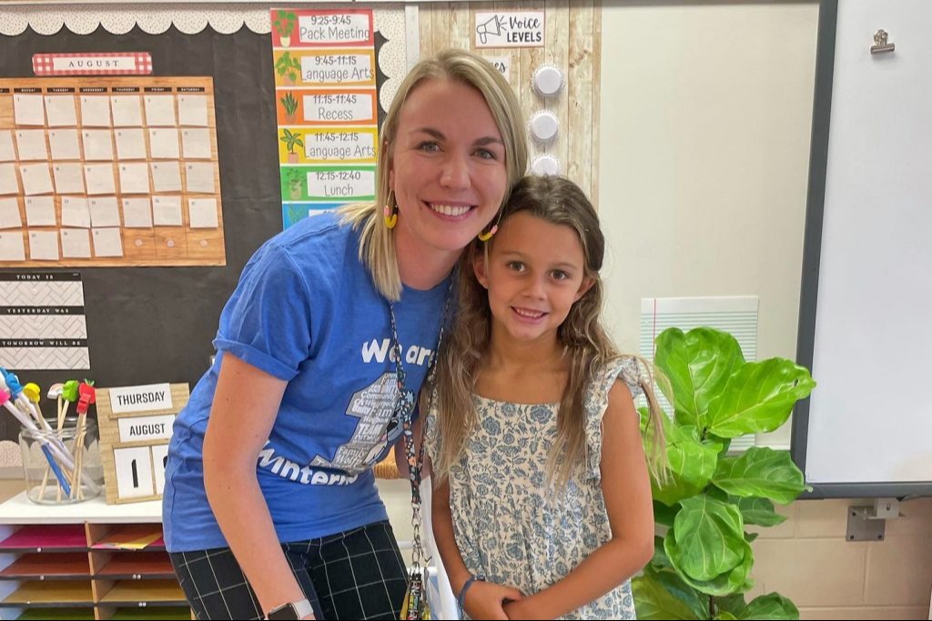 Teacher smiling with young student in classroom