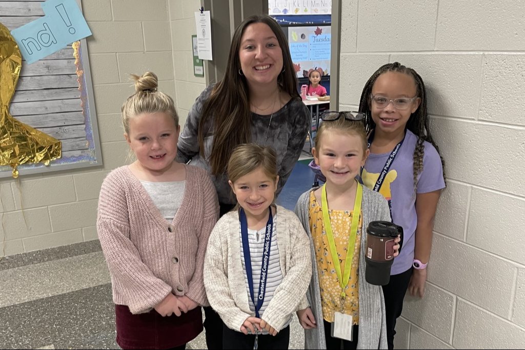 Teacher smiling with four young students