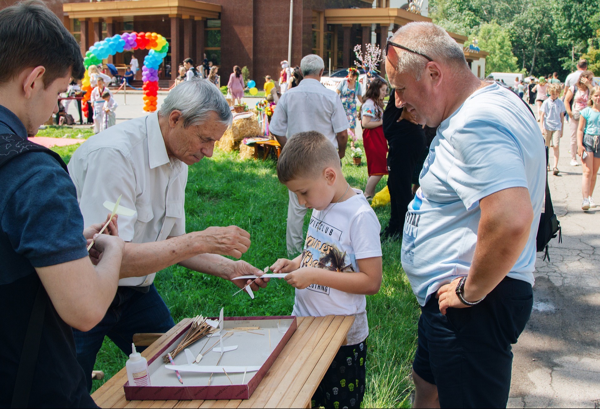 Two men helping a student outdoors at a fair.