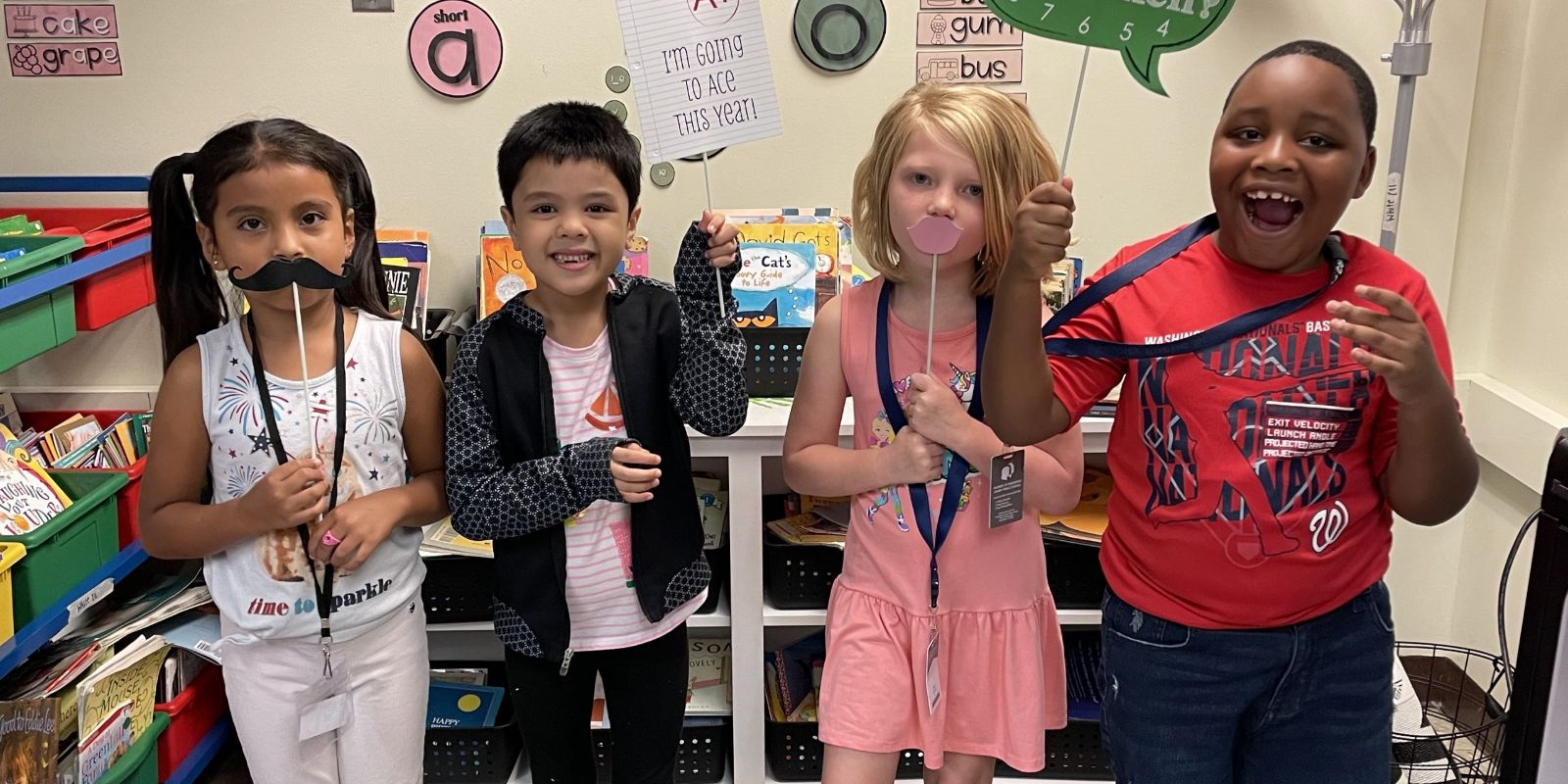 Four children smiling and holding silly props