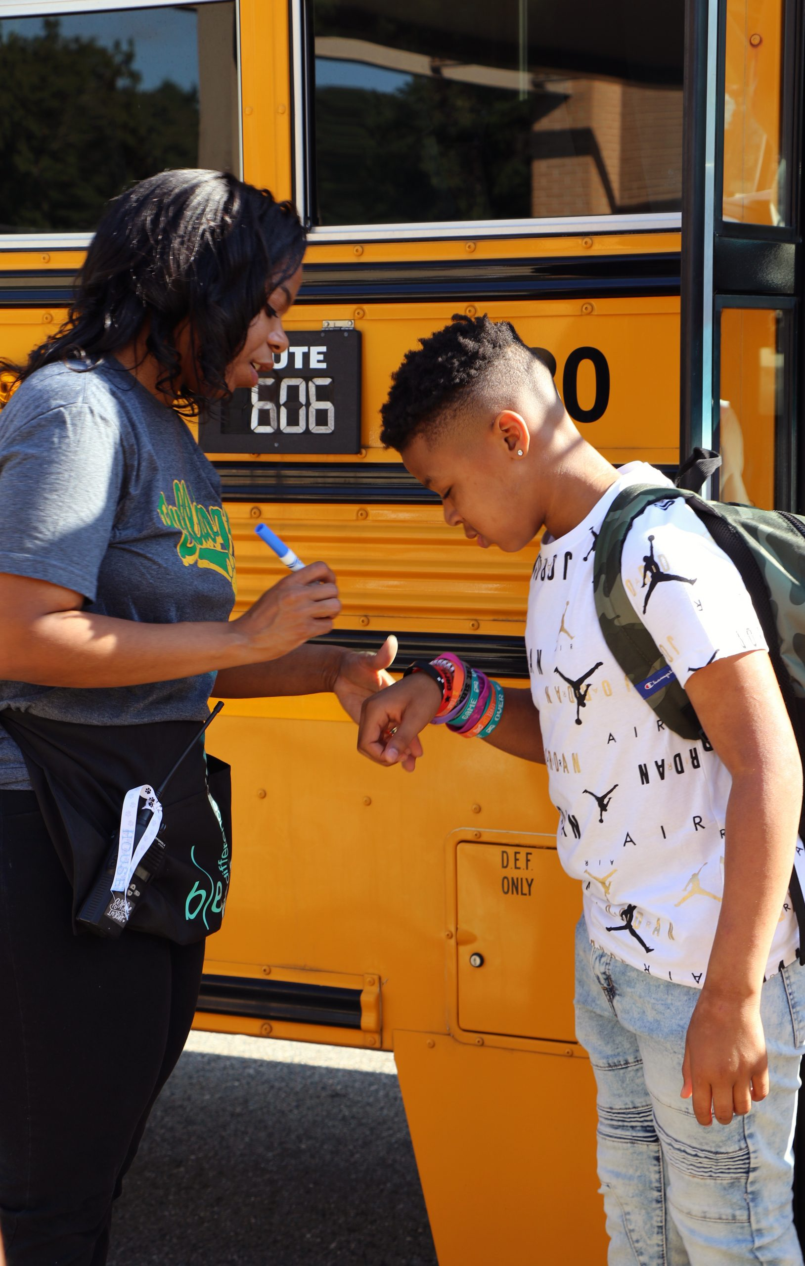 Bus attendant marking hand of student