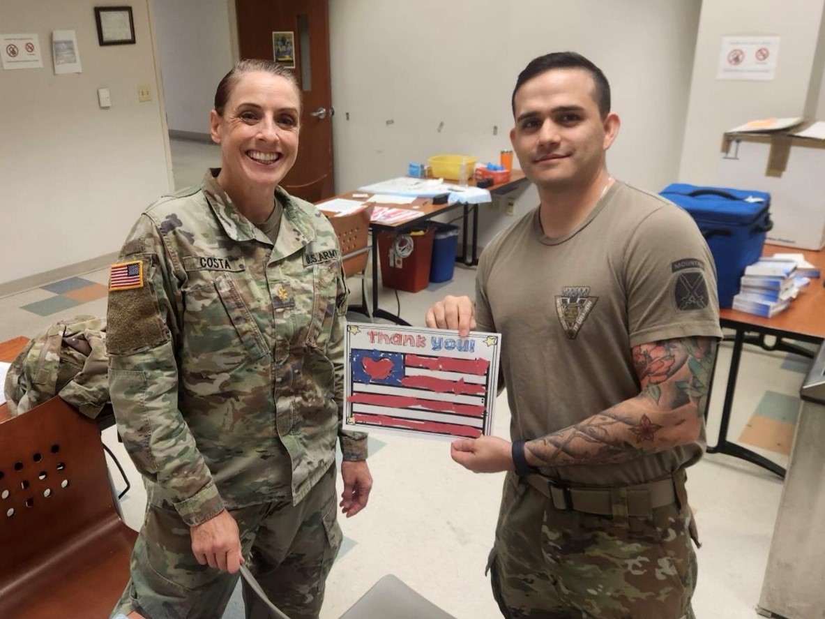 Two military officers holding a thank you card