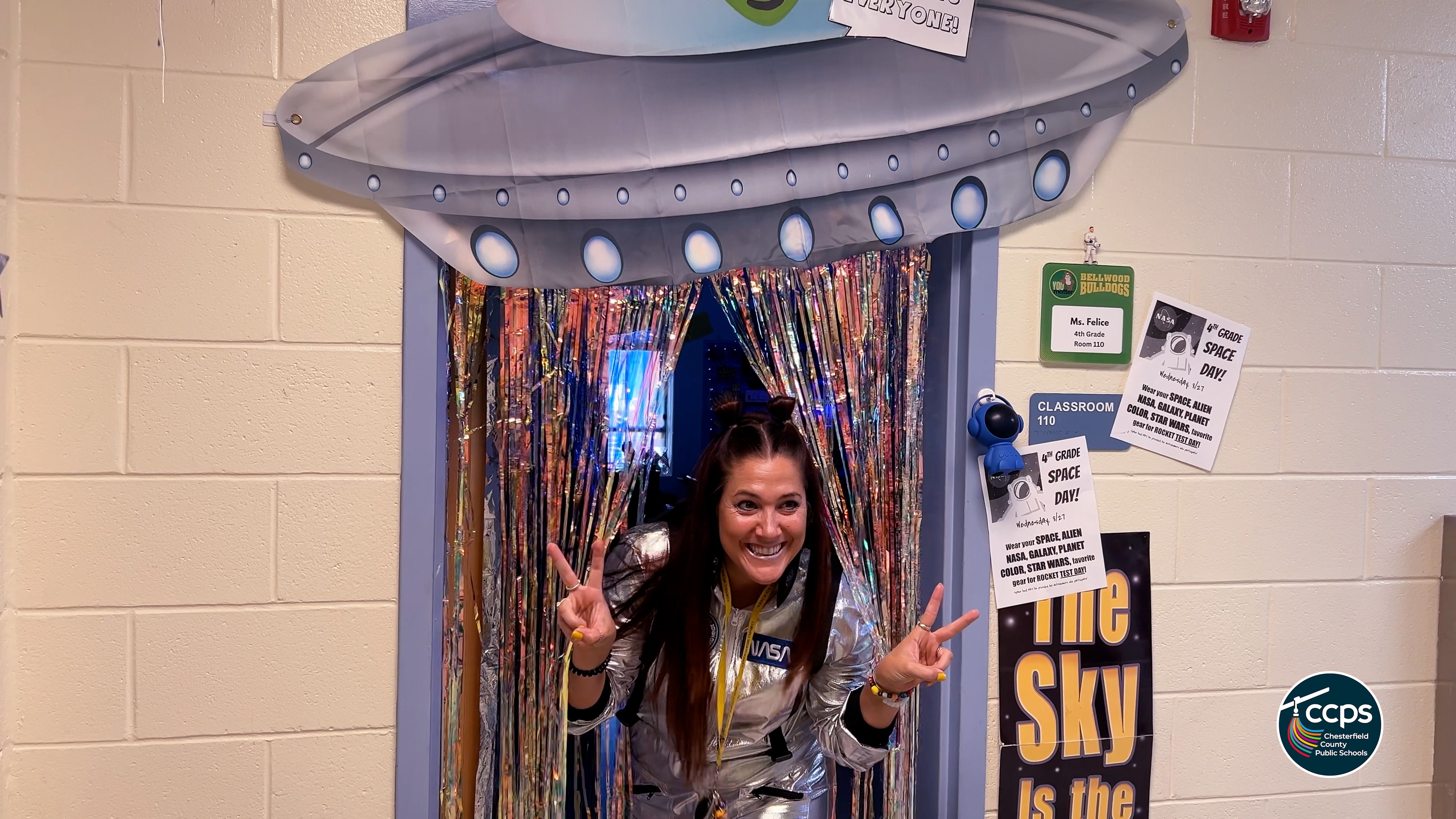 Teacher in spacesuit peaking out from under a UFO