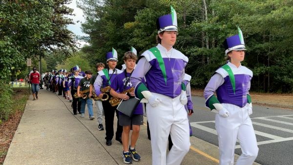 A marching band lined up on a sidewalk