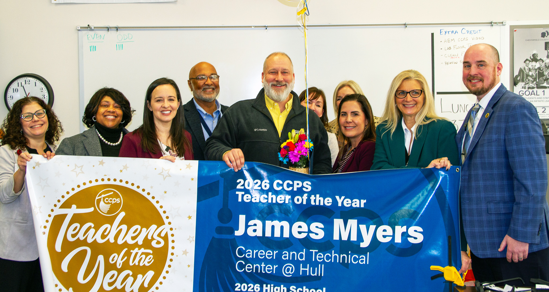 group of leadership pose with teacher and a teacher of the year banner