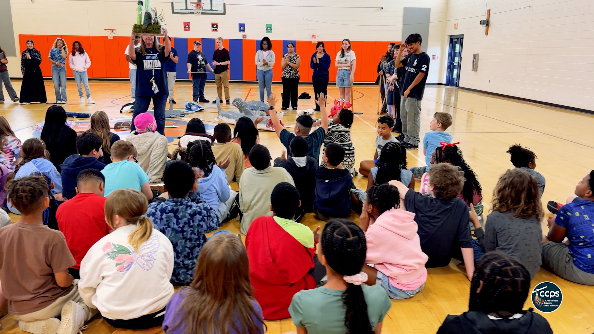 A group of students looking at a teacher holding up a model of a  deep sea creature