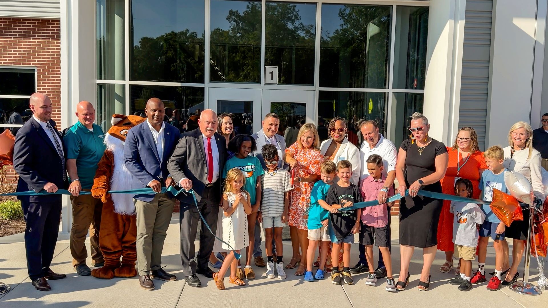 A group of school and county leaders and families cutting a ribbon