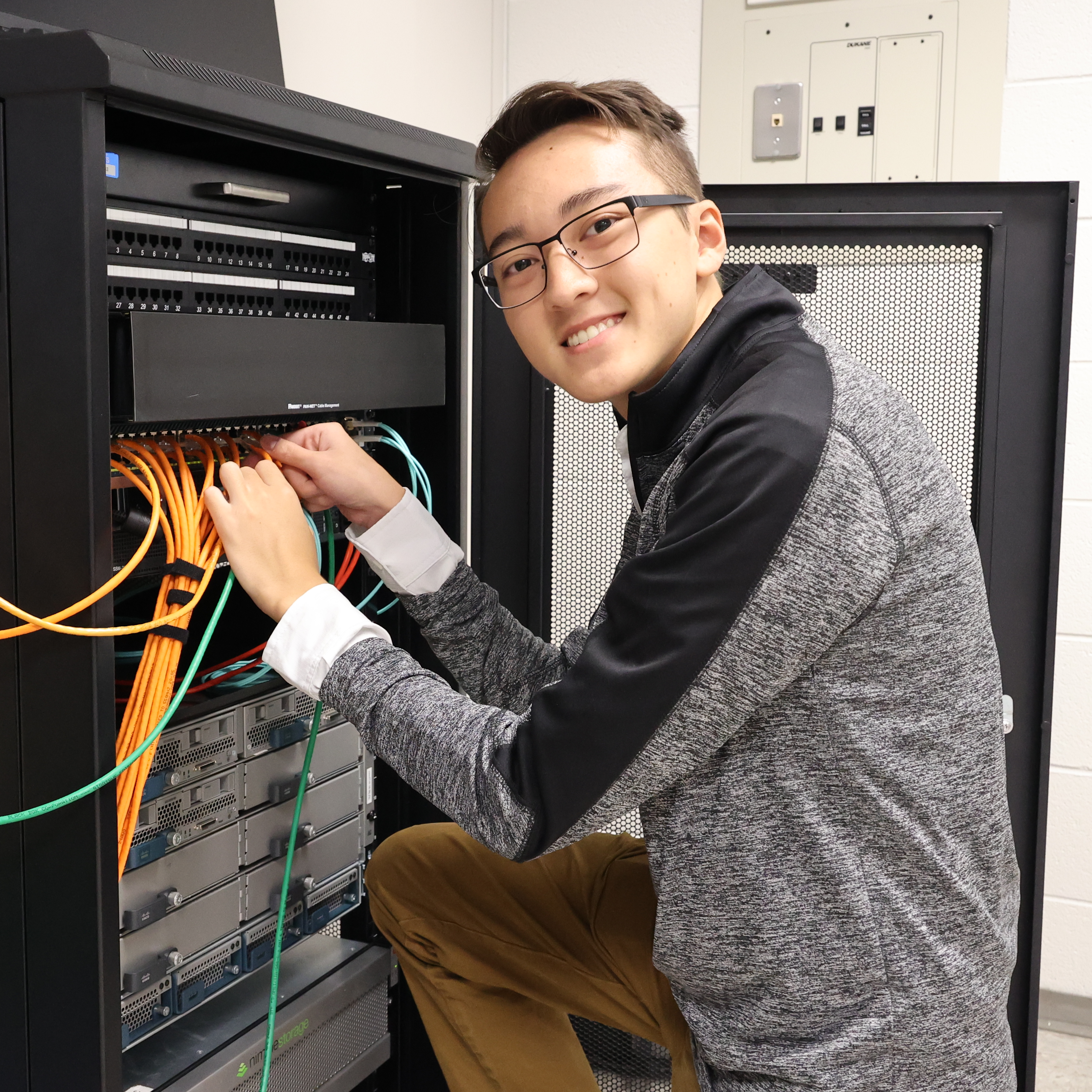 An Asian male student holds bands of networking cords.