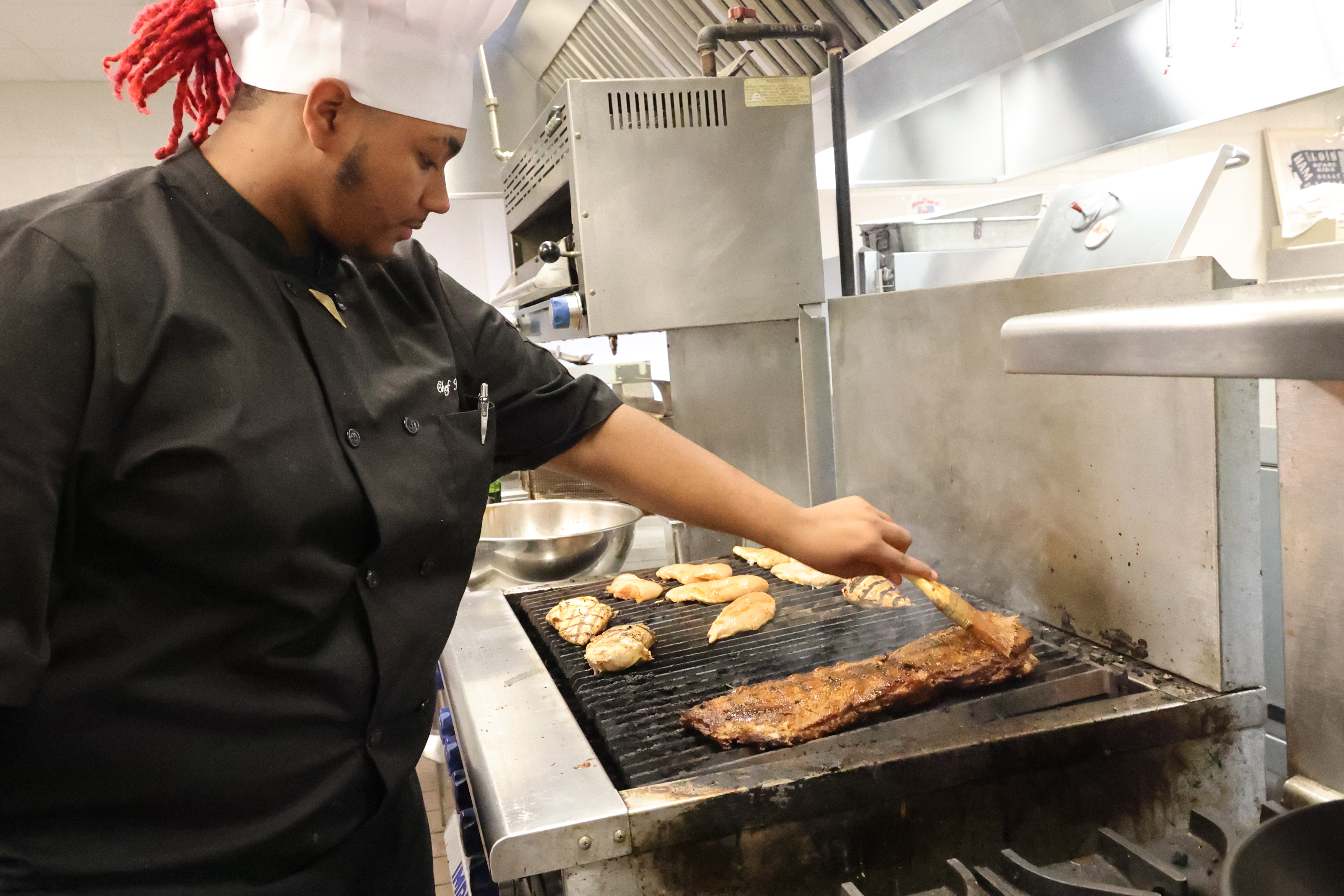 A Black male is basting a rack of ribs with barbeque sauce on the stove