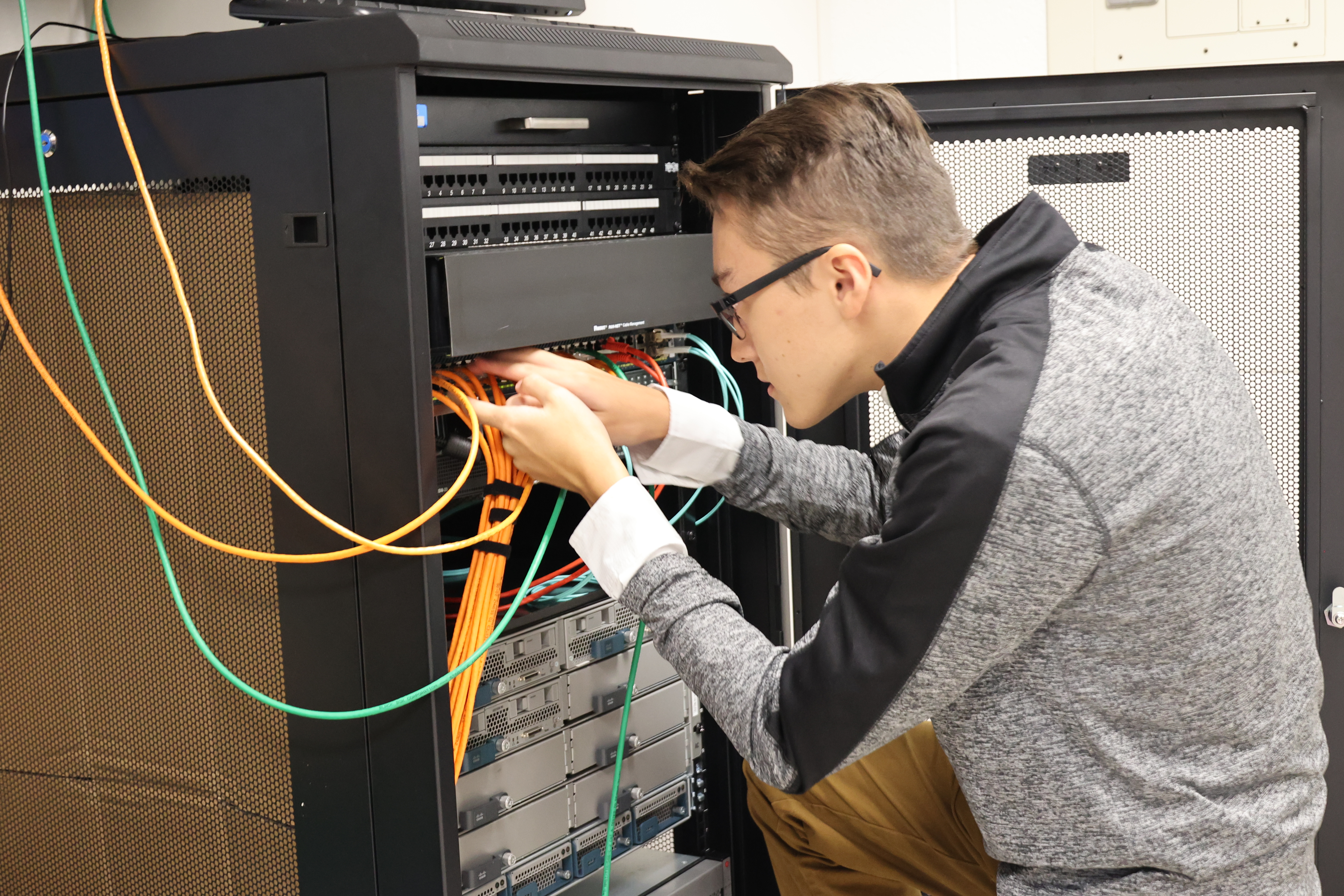 A male student is separating networking cords in its housing unit.