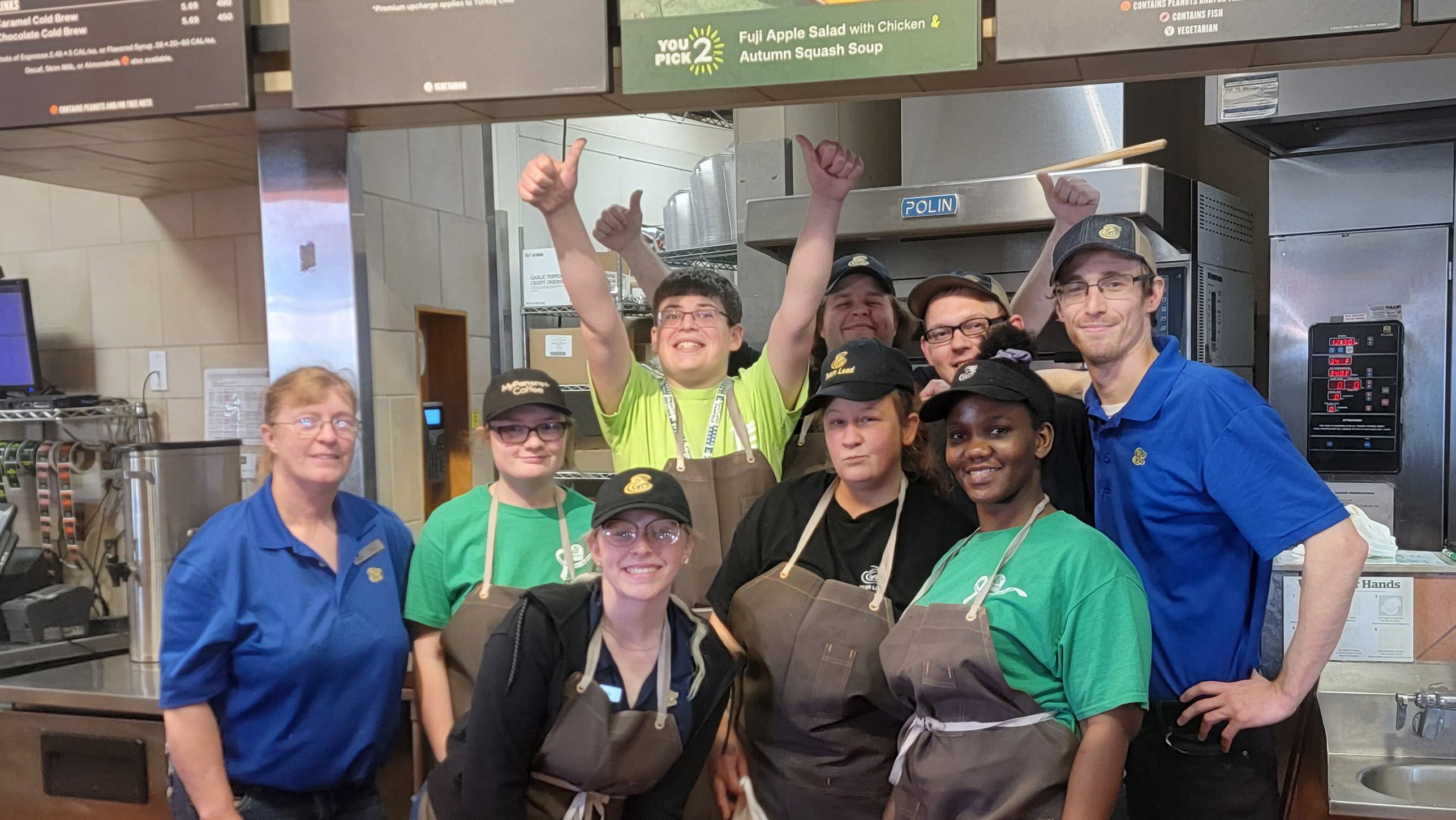 An Employability Prep student raises his hand in celebration among a group of his colleagues at Panera Bread