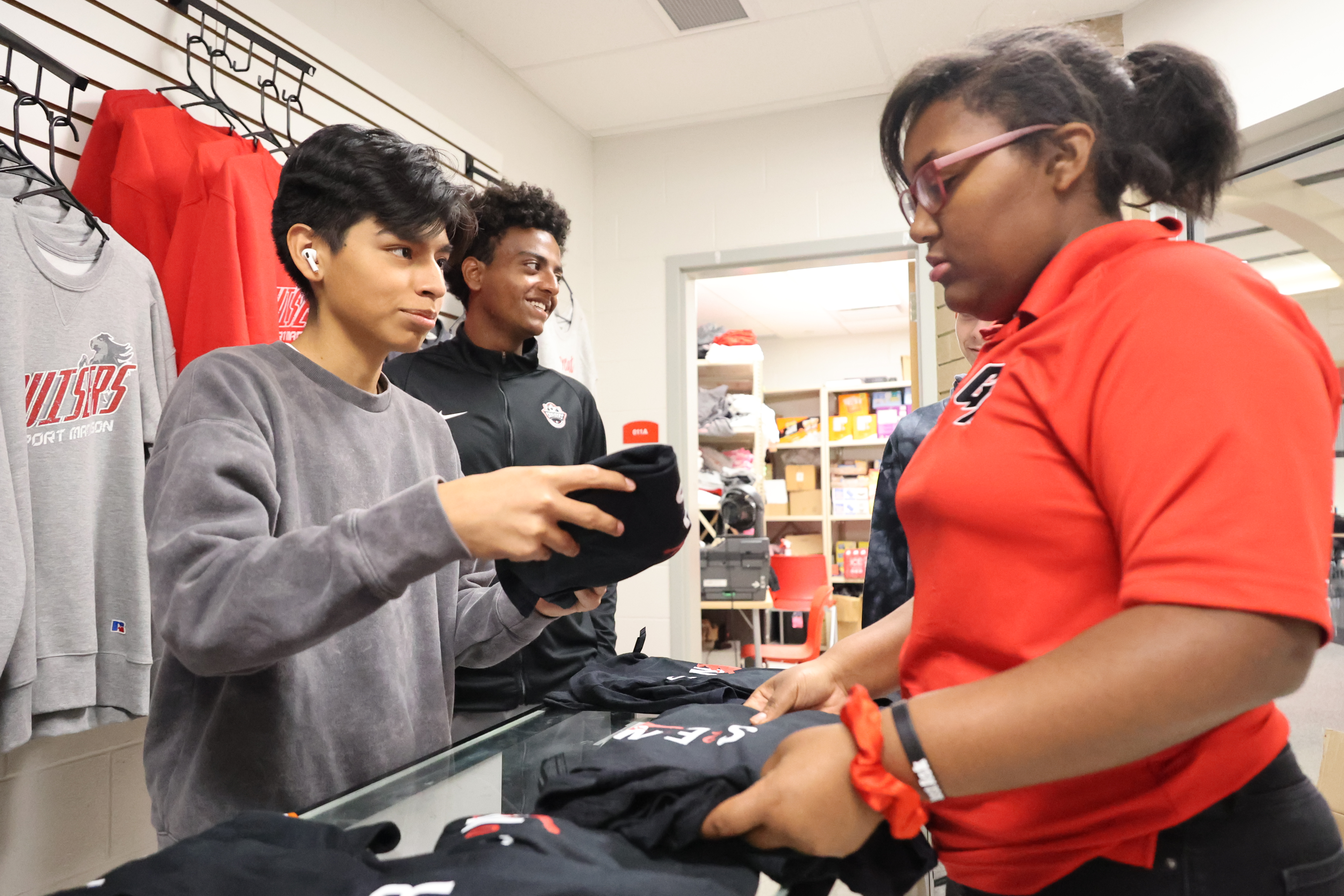 A Hispanic male student and a Black female student are organizing items on the counter before putting them on display.