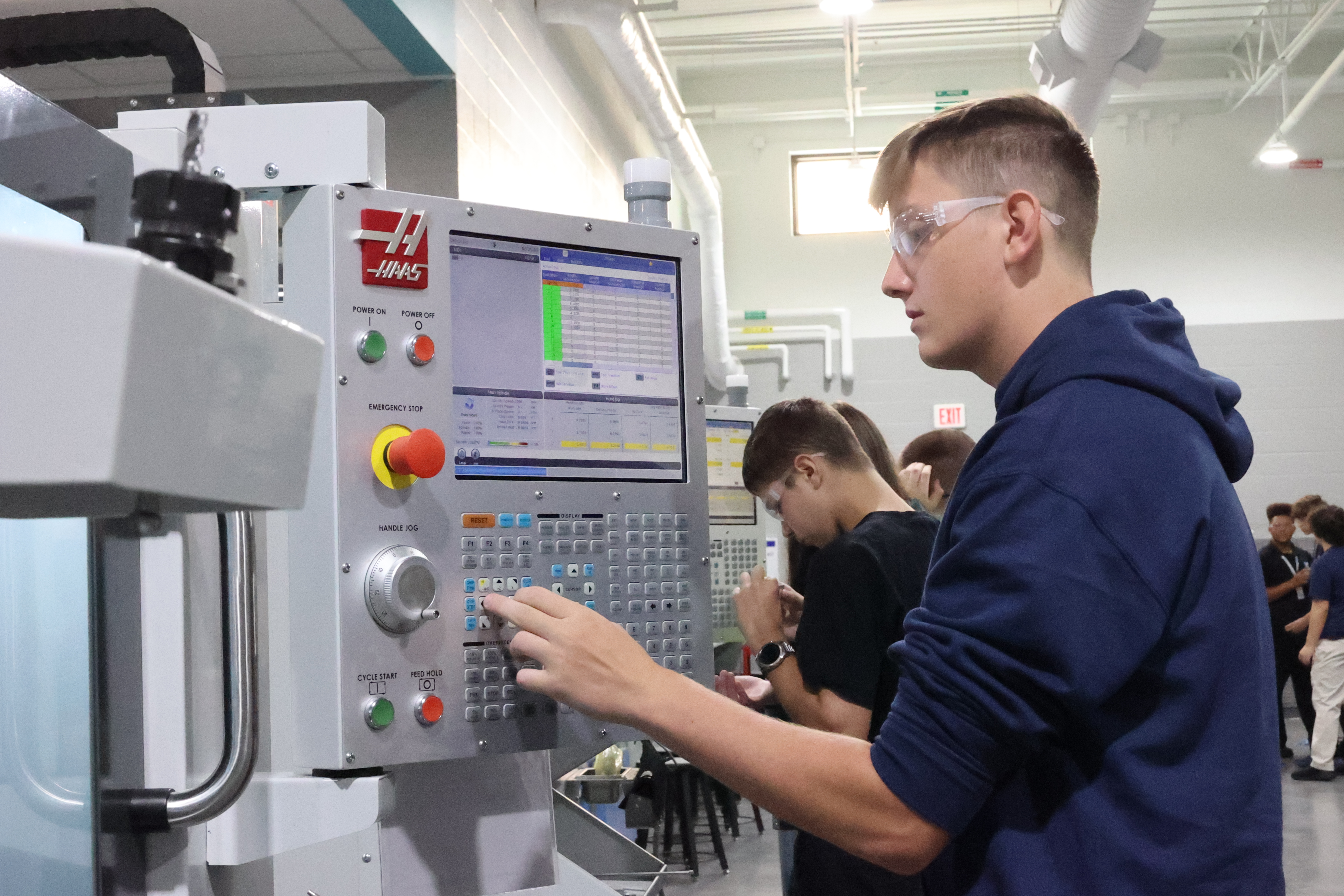 A student is examining the control panel of a machine he is operating.