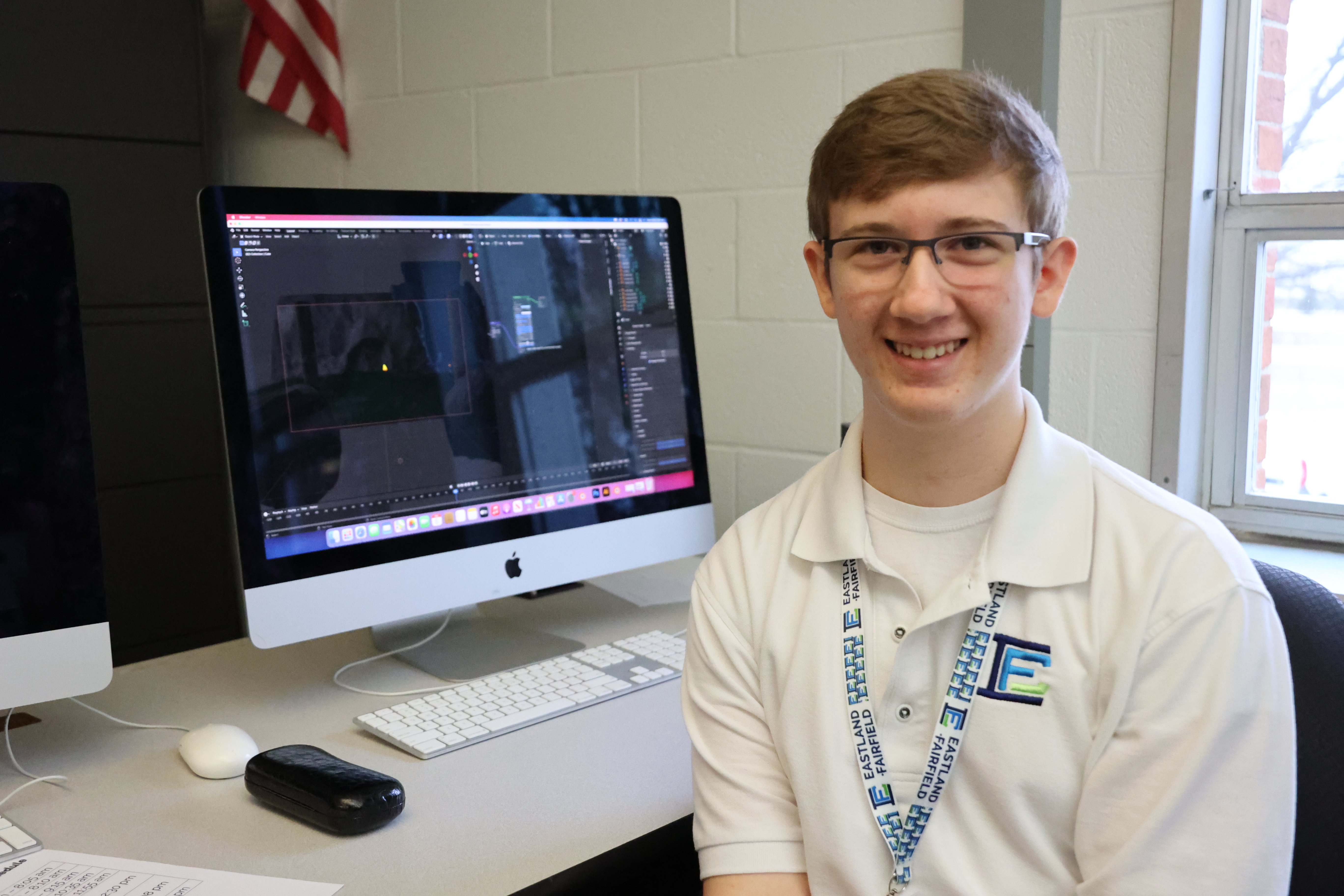 A student in the Interactive Media lab smiles at his work station