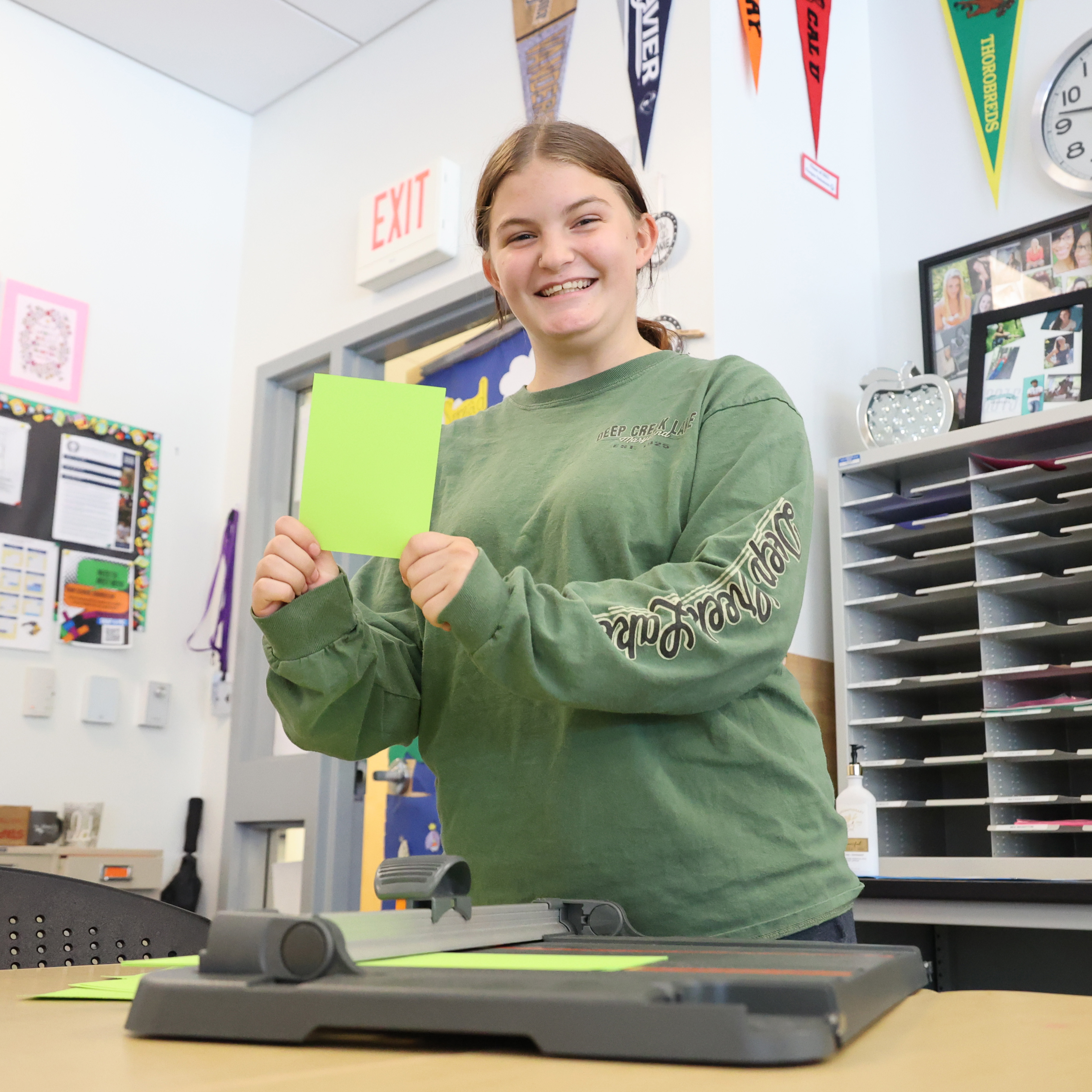 A female student shows the green paper that she just sliced using a paper cutter.