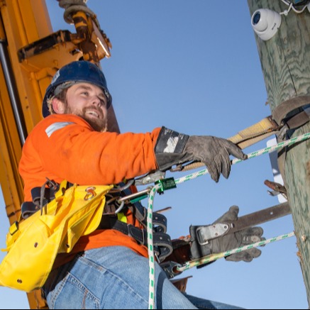 Worker that is elevated and strapped to an electrical pole for safety