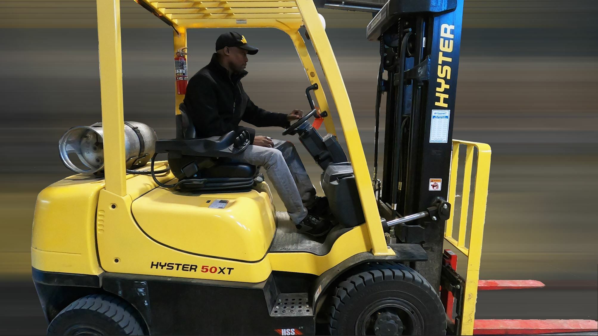 A Black man is operating a fork lift vehicle.