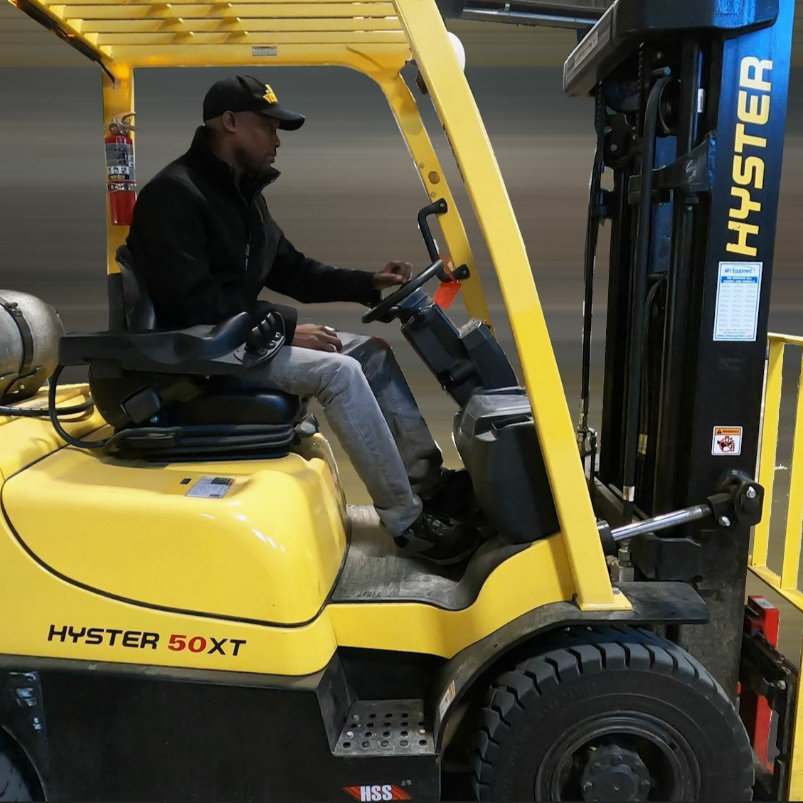 A Black man is operating a yellow fork lift.