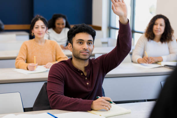 A Middle Eastern man raises his hand in a classroom setting.