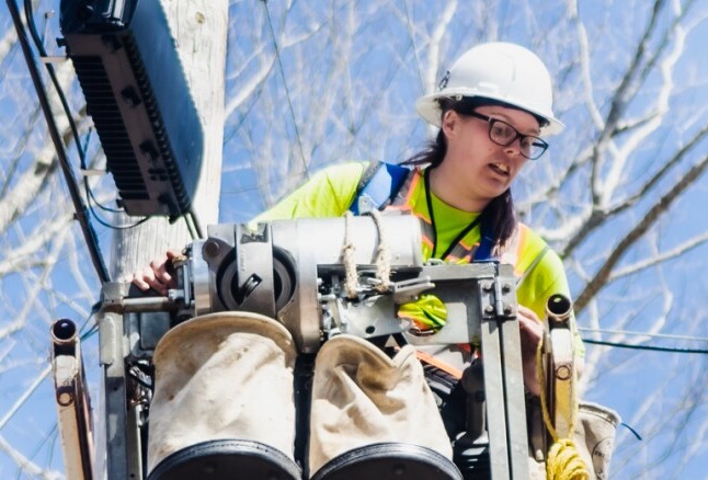 Female installing fiber lines in a scissor lift bucket