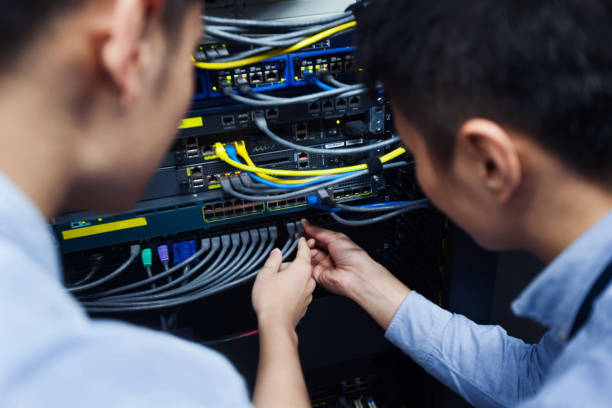 Two individuals examining fiber wires in a rack.