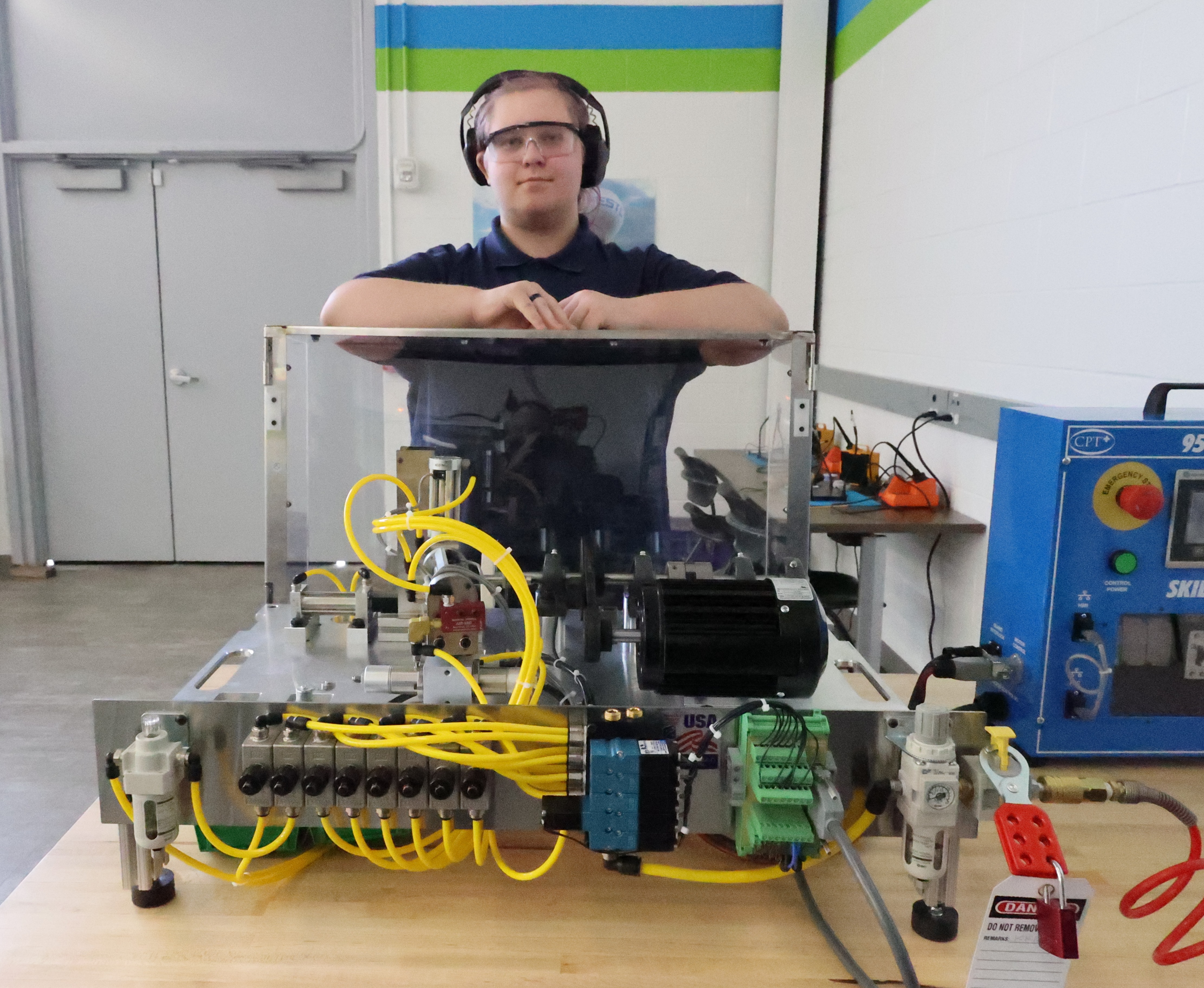 A student is leaning on a piece of machinery in the Robotics lab at ECC.