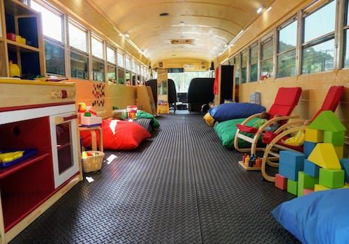 A converted bus with comfy chairs and educational toys